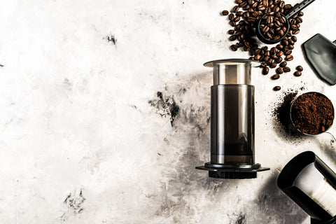 AeroPress coffee maker with whole beans and ground coffee